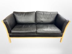 A Danish beech framed three seater settee with black leather cushions,