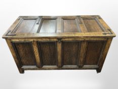 A reproduction panelled oak and cast-iron-mounted blanket chest on castors,