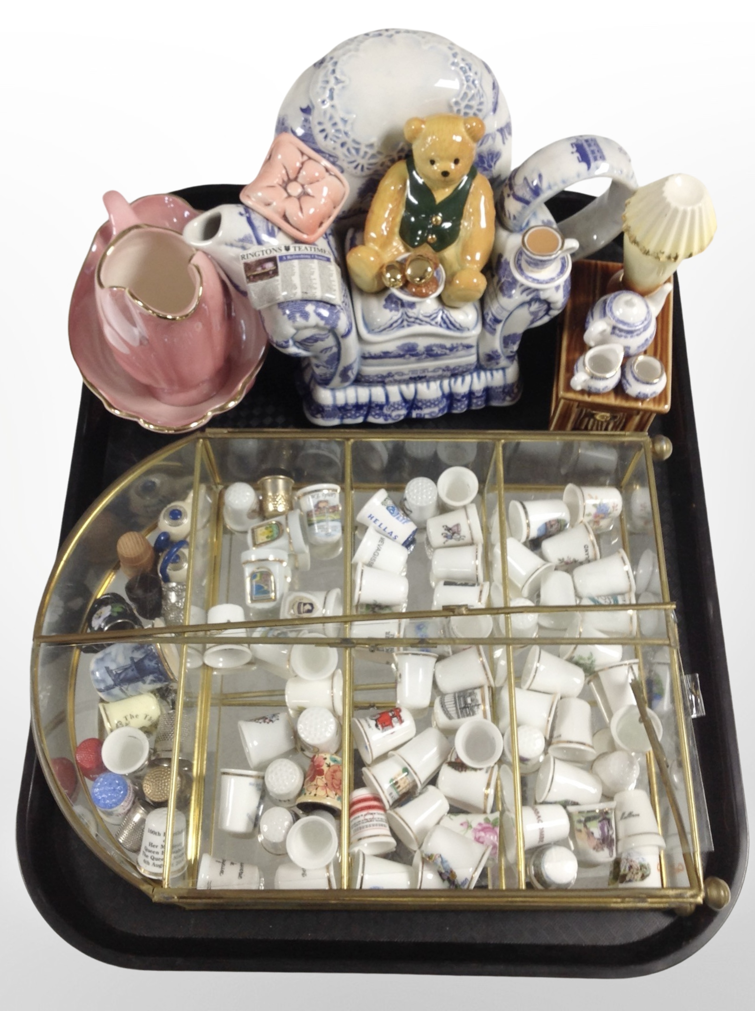 A brass and glass display stand containing assorted ceramic thimbles,