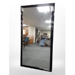 A contemporary bevelled mirror in high gloss ebonised frame,