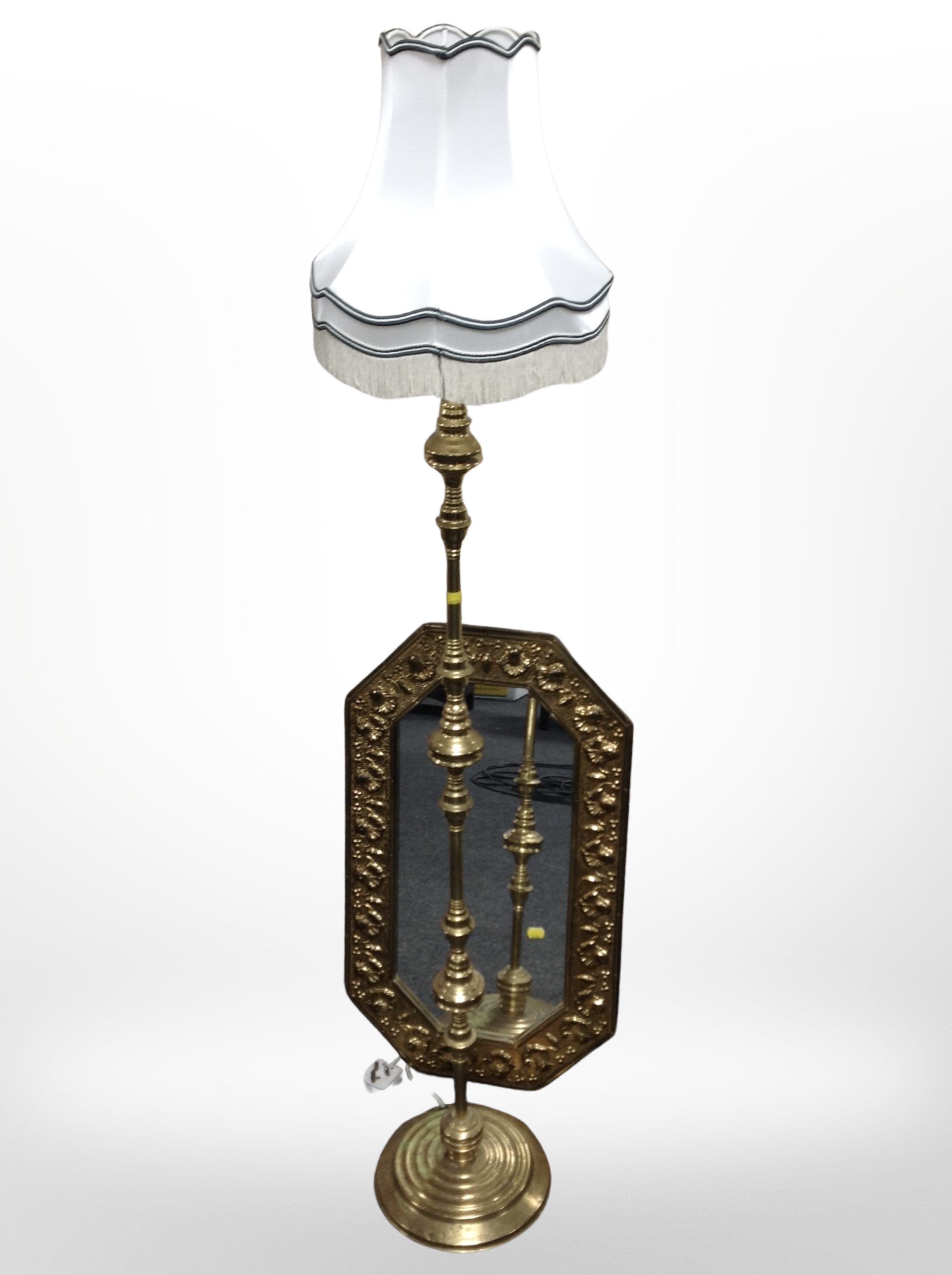 An embossed brass octagonal mirror, and a brass standard lamp.