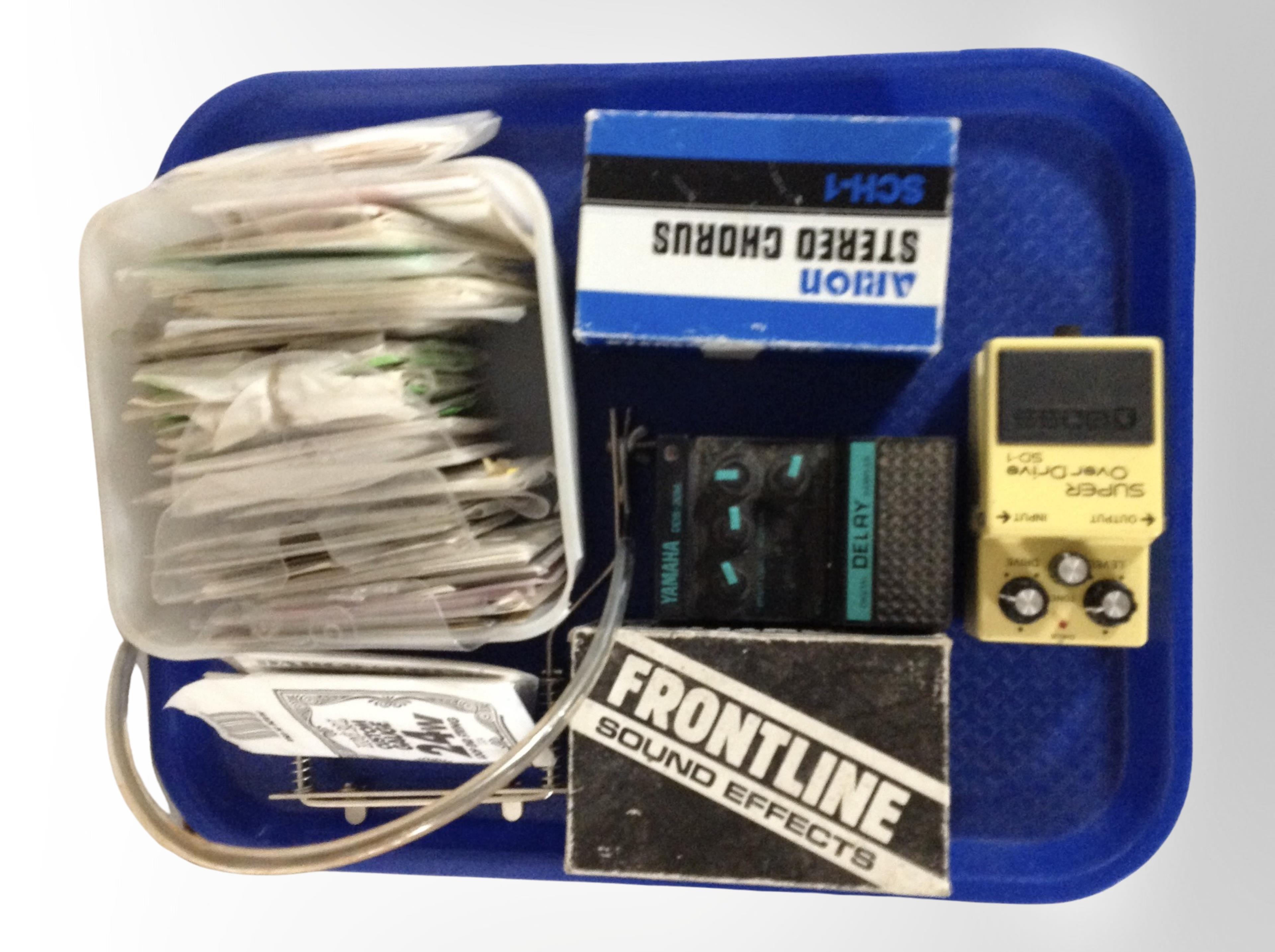 A group of guitar effect pedals, guitar and banjo strings.
