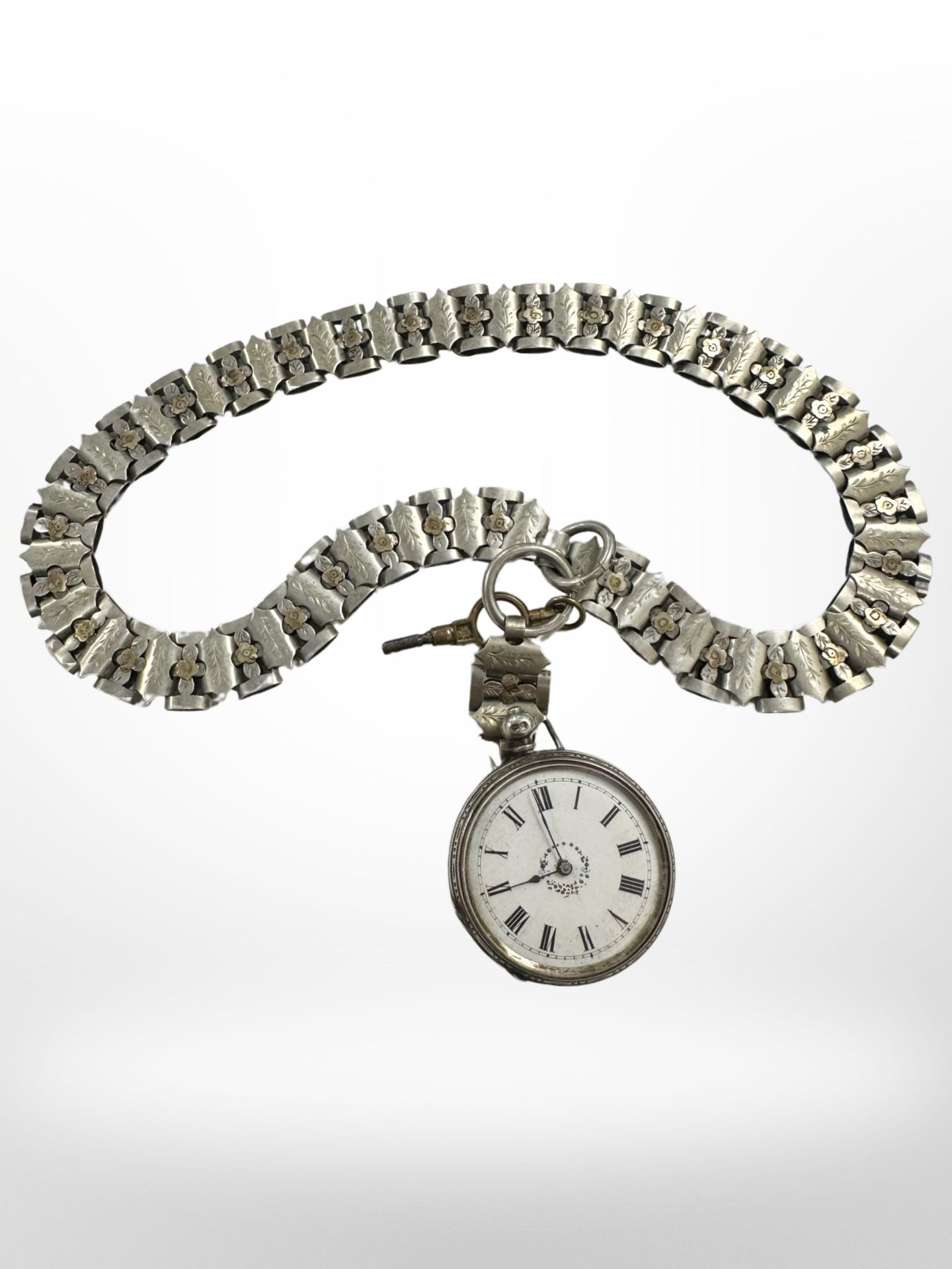 A continental silver fob watch upon an ornate fancy-link chain