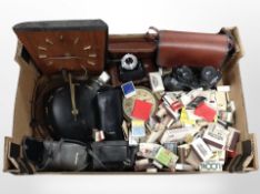 A box containing continental teak timepiece, vintage and later cameras, binoculars, matchbooks, etc.