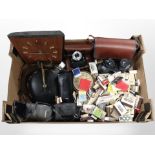 A box containing continental teak timepiece, vintage and later cameras, binoculars, matchbooks, etc.