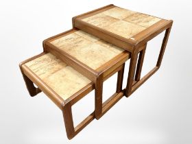A nest of three teak tile-topped tables, width 54cm.