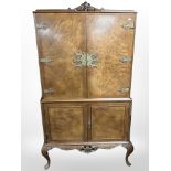 A 20th-century burr walnut brass-mounted drinks cabinet on cabriole legs,