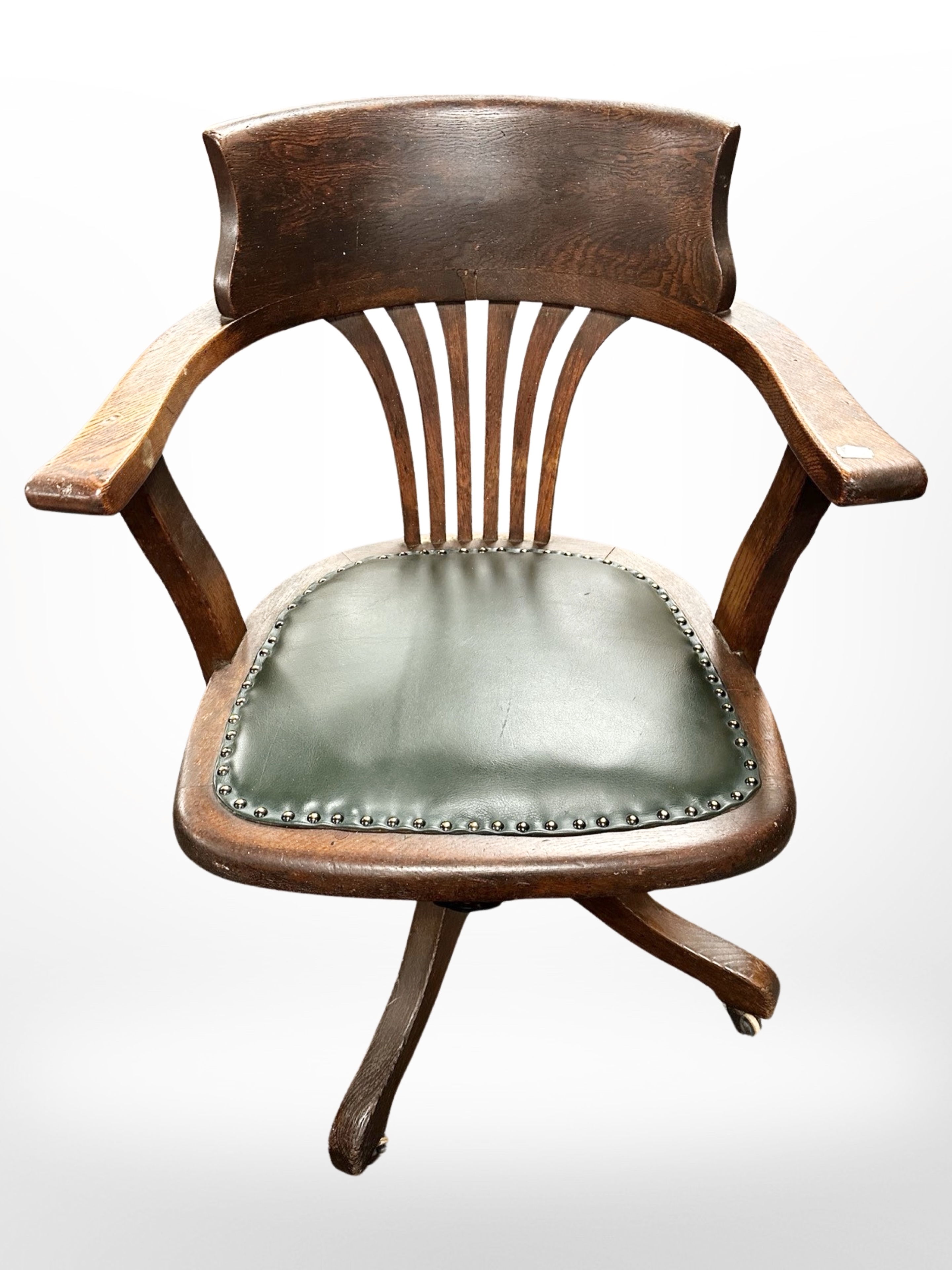 An Edwardian oak swivel office armchair with green studded leather seat, width 62cm.