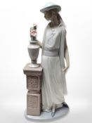 A Lladro figure of a lady standing beside a vase of flowers on pedestal, associated box.