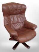 A Scandinavian stitched brown leather and stained wood swivel armchair