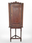 A 19th century carved oak stained pine corner cabinet on stand,
