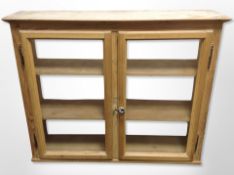 An early 20th century pine double door glazed cabinet,