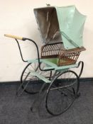 A early 20th century painted wood and wrought metal pram with wicker and canvas canopy