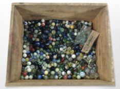 A pine crate containing a large quantity of vintage glass marbles