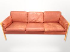 A Danish beech and bergere framed three seater settee with terracotta stitched leather cushions,