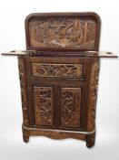 An Oriental heavily carved camphor wood drinks cabinet,