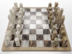 A polished stone chess board with pieces,