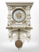 A Continental cream and gilt eight day wall clock with enamelled dial, pendulum,