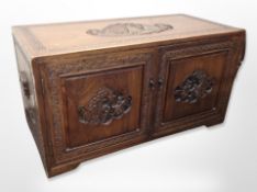A carved camphor wood double door low chest fitted four internal drawers with brass drop handles,