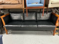 A late 20th century black stitched leather and wooden framed three seater settee,