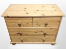 A contemporary pine four drawer low chest on bun feet,