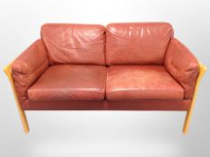 A Danish beech and bergere framed two seater settee with terracotta stitched leather cushions,