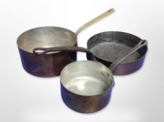 Three copper cooking pans with cast iron and brass handles,