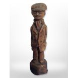 A hand carved figure of a man wearing a flat cap,