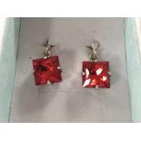 A pair of silver earrings set with red faceted stones