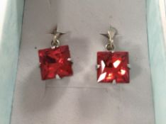 A pair of silver earrings set with red faceted stones
