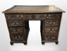 A George III and later carved oak eight drawer kneehole desk,