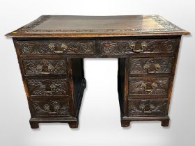 A George III and later carved oak eight drawer kneehole desk,