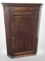 A George III inlaid oak hanging corner cabinet,