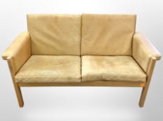A 20th century Danish oak framed tan leather two seater settee designed by Hans J Wegner,