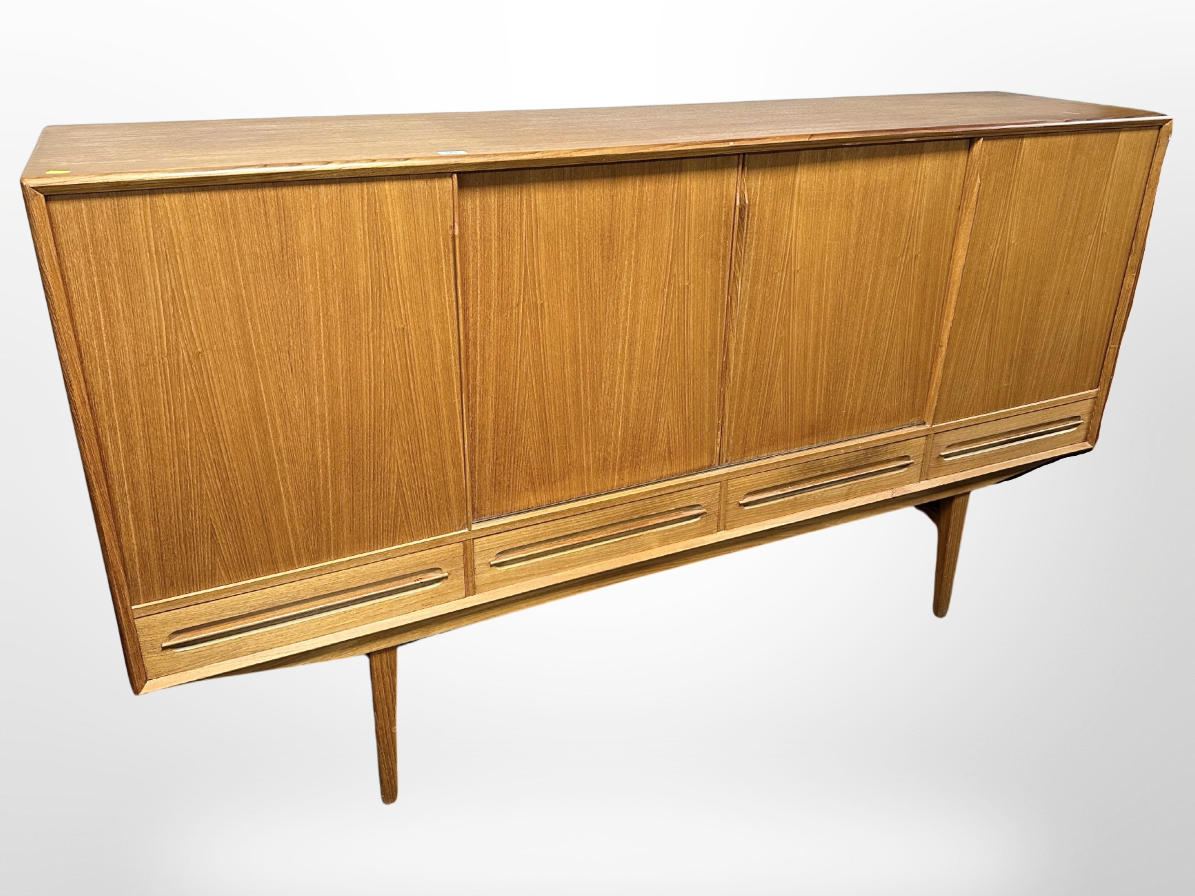 A 20th century Danish teak sliding door sideboard, fitted with four drawers raised on tapering legs,