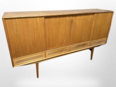 A 20th century Danish teak sliding door sideboard, fitted with four drawers raised on tapering legs,
