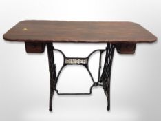 A cast iron Singer treadle sewing machine base with later rustic pine top,