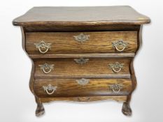 A continental oak three-drawer serpentine front bombe commode,
