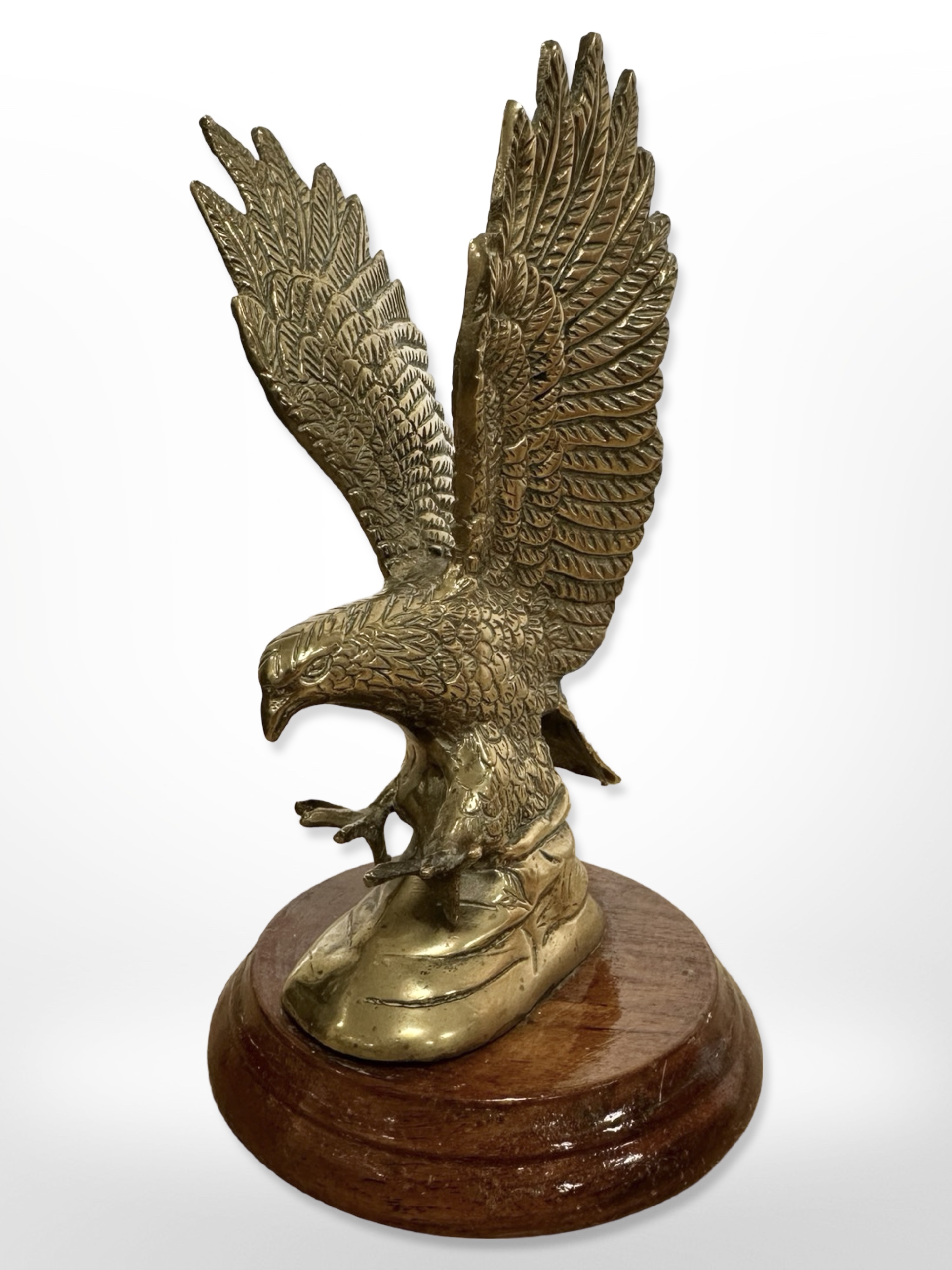 A cast brass figure of an eagle on turned wooden plinth, height 16.