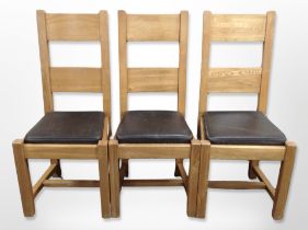 A set of eight contemporary oak dining chairs with brown stitched leather seat pads