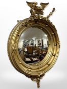 A Regency-style gilt gesso convex porthole mirror, surmounted by an eagle,