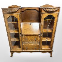 A 1920's carved oak sunk-centre bureau with leaded glass doors,