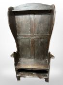 A 19th-century panelled oak wingback hall seat, 96cm wide x 39cm deep x 168cm high.