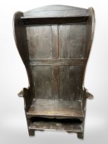 A 19th-century panelled oak wingback hall seat, 96cm wide x 39cm deep x 168cm high.