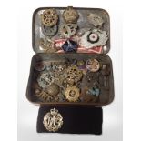 A tin of military cap badges and other decorations.