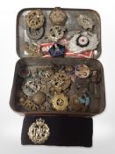 A tin of military cap badges and other decorations.
