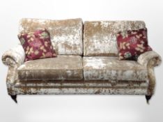 A contemporary Victorian style three seater settee in plush fabric with two cushions raised on