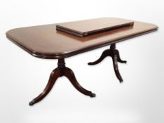 A reproduction mahogany extending dining table with one leaf,