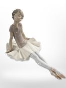 A Lladró figure of a seated ballerina.