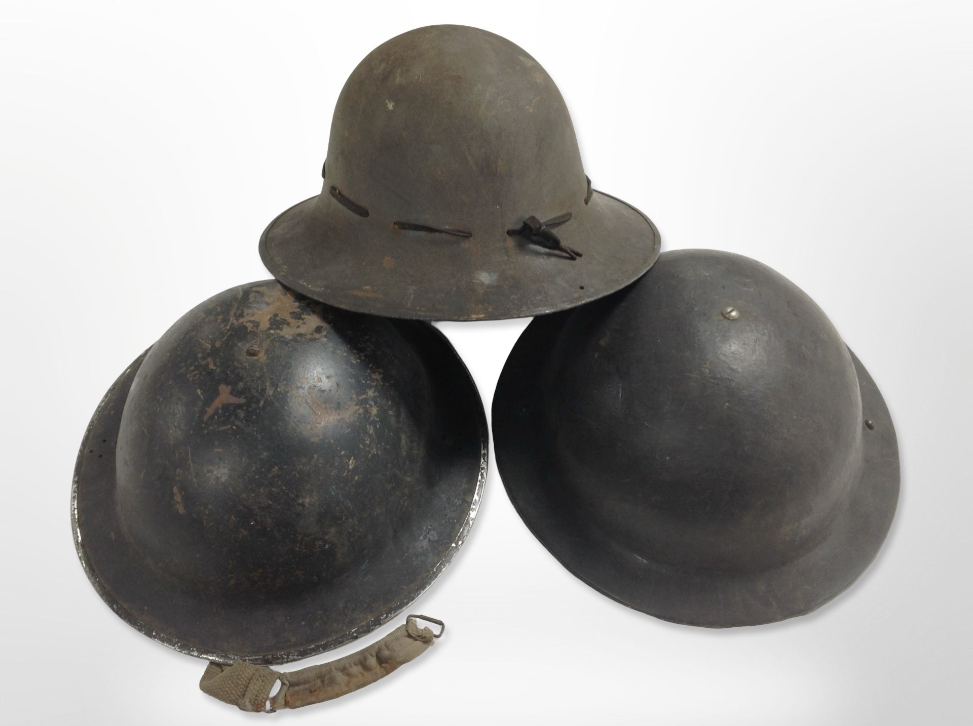 Three 20th-century military tin helmets.